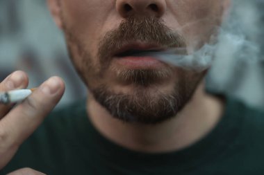 Arka planda sigara içen adam, yakın plan.