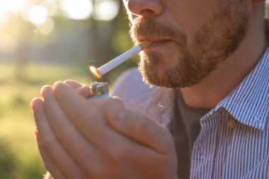 Sigarayı çakmakla yakan adam, yakın plan.