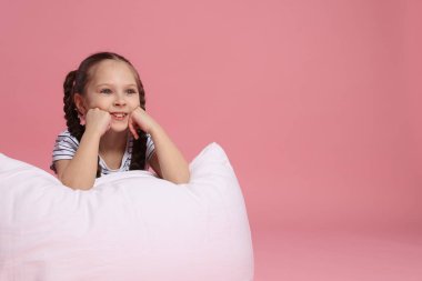 Pembe arka planda yastığı olan tatlı bir kız. Metin için boşluk