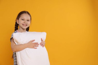 Turuncu arka planda yastığı olan tatlı bir kız. Metin için boşluk