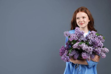 Gri arka planda bir demet leylak çiçeği olan güzel bir genç kız. Metin için boşluk