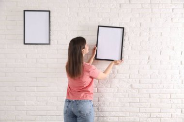 Beyaz tuğla duvara boş çerçeveler asan kadın, arka plan