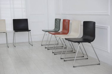 Bekleme odasındaki beyaz duvarın yanındaki renkli sandalyeler