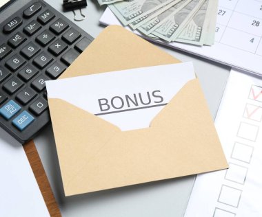Açık gri arkaplan üzerinde bonus, para, hesap makinesi ve kağıt işleriyle zarf, yakın plan