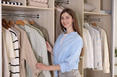 Gülümseyen moda tasarımcısı stüdyoda kıyafet seçiyor.