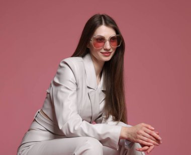 Pembe arka planda şık giyinmiş güzel bir kadının moda portresi.