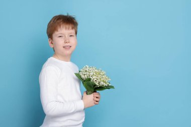 Açık mavi arka planda vadideki güzel çiçekleri olan bir buket çocuk. Metin için boşluk