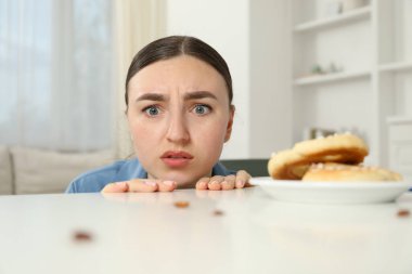 Beyaz masadaki hamamböceklerine ve krakerlere bakan genç bir kadın şok oldu. Haşere sorunu