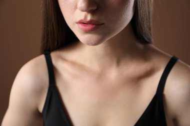 Kahverengi arka planda güzel köprücük kemiği olan kadın, yakın plan.