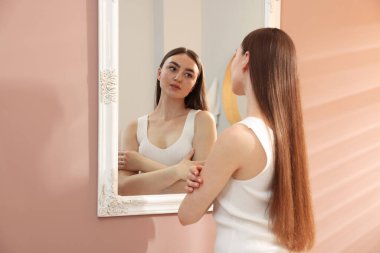 Güzel bir kadın aynada kendine bakıyor.