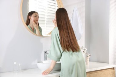 Güzel bir kadın aynada kendine bakıyor.