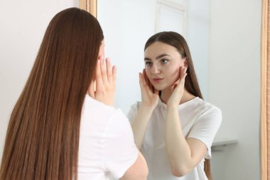 Güzel bir kadın aynada kendine bakıyor.