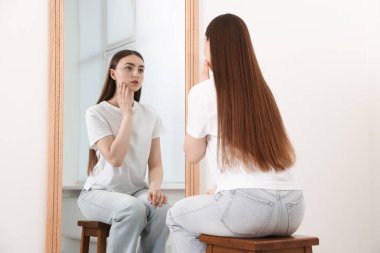 Güzel bir kadın aynada kendine bakıyor.