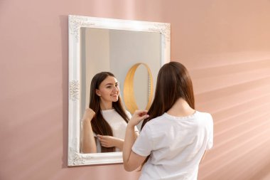 Güzel bir kadın aynada kendine bakıyor.