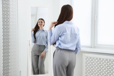 Güzel bir kadın aynada kendine bakıyor.