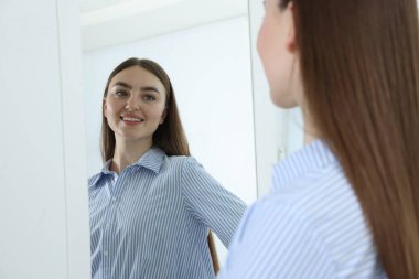 Güzel bir kadın aynada kendine bakıyor.