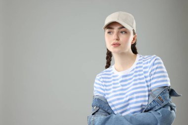 Gri arka planda şık bir beyzbol şapkası olan güzel bir kadın. Metin için boşluk