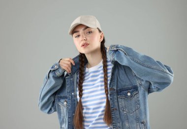 Gri arka planda şık beyzbol şapkalı güzel bir kadın.