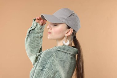 Beyzbol şapkalı güzel bir kadın bej arka planda.