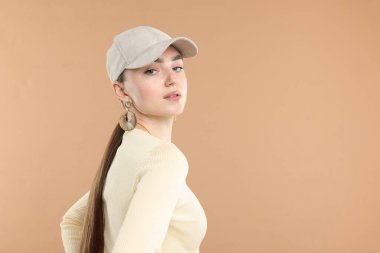 Bej arka planda şık bir beyzbol şapkası olan güzel bir kadın. Metin için boşluk