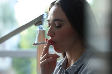 İçeride sigara içen bir kadın, yakın plan. Kötü alışkanlık.