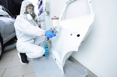 Kaportacının kapısını boyayan bir işçi.