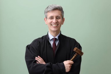 Yeşil arka planda tokmakla gülümseyen yargıç portresi