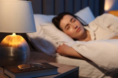 Evde uyuyan genç kadın, gözlük ve kitaba odaklan.