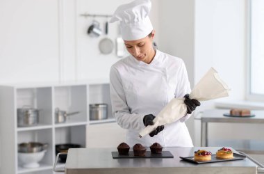 Şekerci mutfakta kremalı kekleri dekore ediyor.