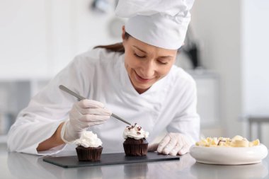 Şekerci, mutfakta çikolata parçalarıyla kek süslüyor.