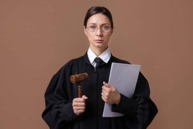 Açık kahverengi arkaplanlı çekiç ve belgelerle hakim