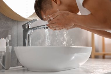 Tuvalette yüzünü yıkayan bir adam.