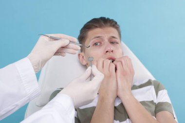 Korkan adamın açık mavi arka planda dişçiyle randevusu var.