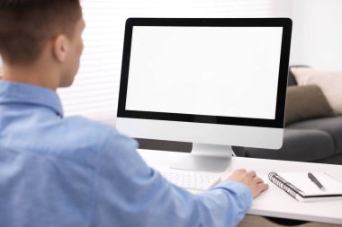 Ofisteki beyaz masada bilgisayarda çalışan bir adam, yakın plan. Tasarım için model