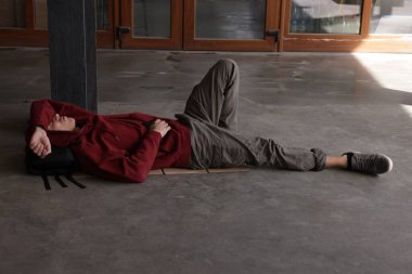 Evsiz bir adam beton zeminde yatıyor.