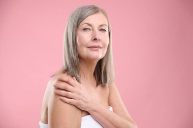 Pembe arka planda sağlıklı ciltli bir kadın.