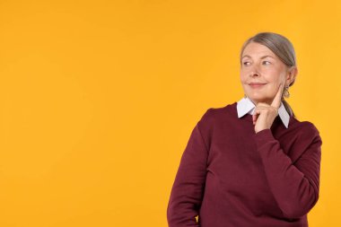 Turuncu arka planda şık giyinmiş mutlu son sınıf kadını, mesaj için yer var.