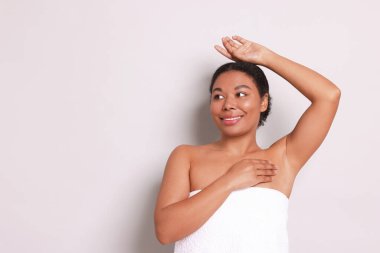 Açık gri arkaplanda epilasyon işleminden sonra kılsız koltuk altını gösteren kadın, metin için boşluk