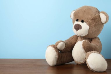 Ahşap masada açık mavi arka planda sevimli bir oyuncak ayı. Metin için boşluk