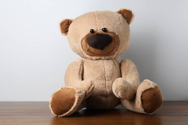 Küçük arka planda tahta masada sevimli bir oyuncak ayı.