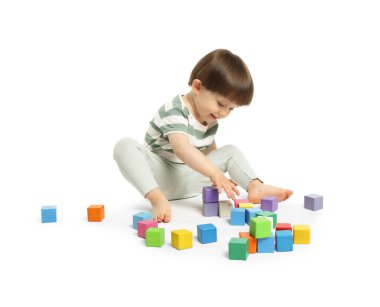 Beyaz arka planda renkli küplerle oynayan sevimli küçük çocuk.