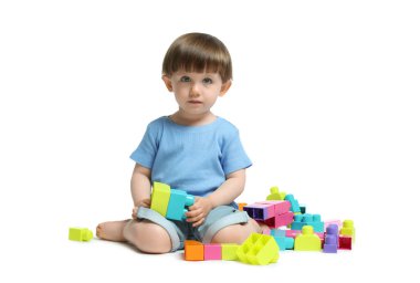 Beyaz arka planda tuğlalarla oynayan sevimli küçük çocuk.