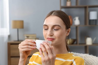 Evde fincandan kahve içen kadın.