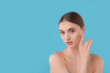 Açık mavi arka planda büyüleyici genç bir kadının portresi. Metin için boşluk