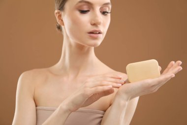 Kahverengi arka planda sabun çubuğu olan güzel kadın, yakın plan.