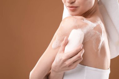 Kahverengi arka planda sabunlu kadın cesedi yıkıyor, yakın plan. Metin için boşluk