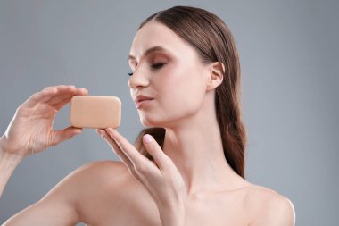 Gri arka planda sabun çubuğu olan güzel kadın, yakın plan.