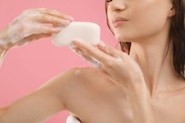 Pembe arka planda köpüklü sabun barlı kadın, yakın plan.