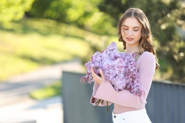 Güzel bir kadın ve açık havada bir demet leylak çiçeği. Metin için boşluk