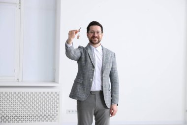 Emlakçının elinde ev şeklindeki anahtarlık var.